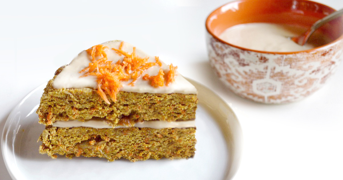 Slice of layered carrot cake topped with frosting and shredded carrot